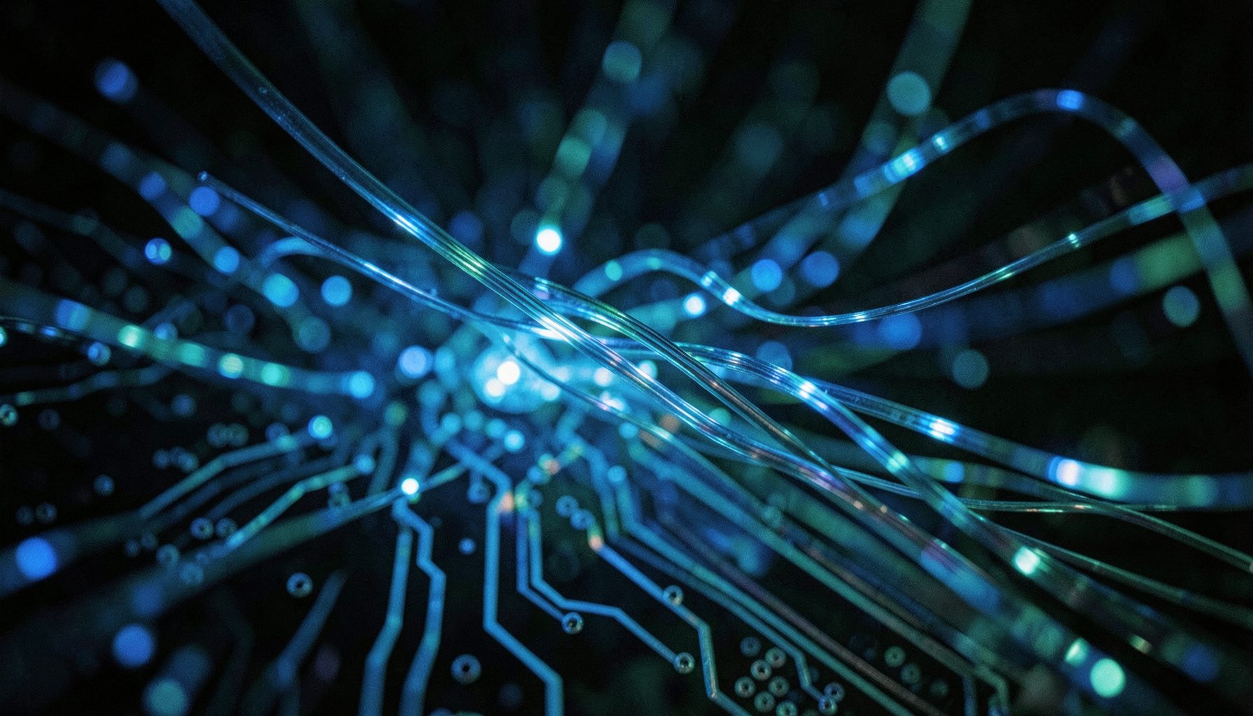 Abstract close-up of glowing fiber-optic strands and circuit traces in deep blue and teal tones, evoking digital connectivity and scientific discovery