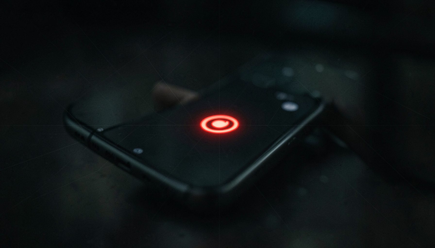 Close-up of a smartphone with a glowing red recording indicator, dark atmospheric background with subtle grid lines, tense privacy-focused mood